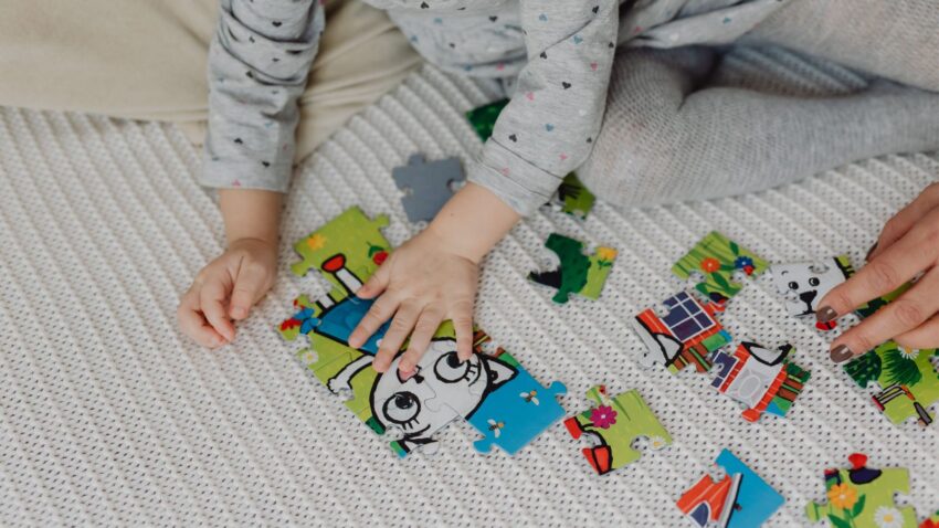 Dziecko układa puzzle w swoim pokoju razem z mamą.
