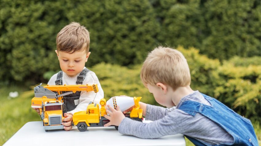 Chłopcy bawią się razem samochodami w ogrodzie.