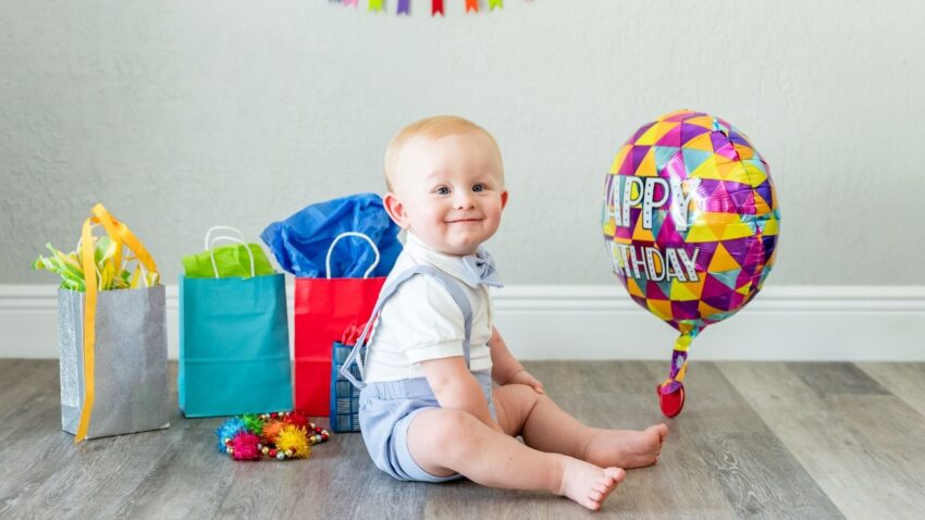 Roczny chłopczyk z balonem z napisem "happy birthday"